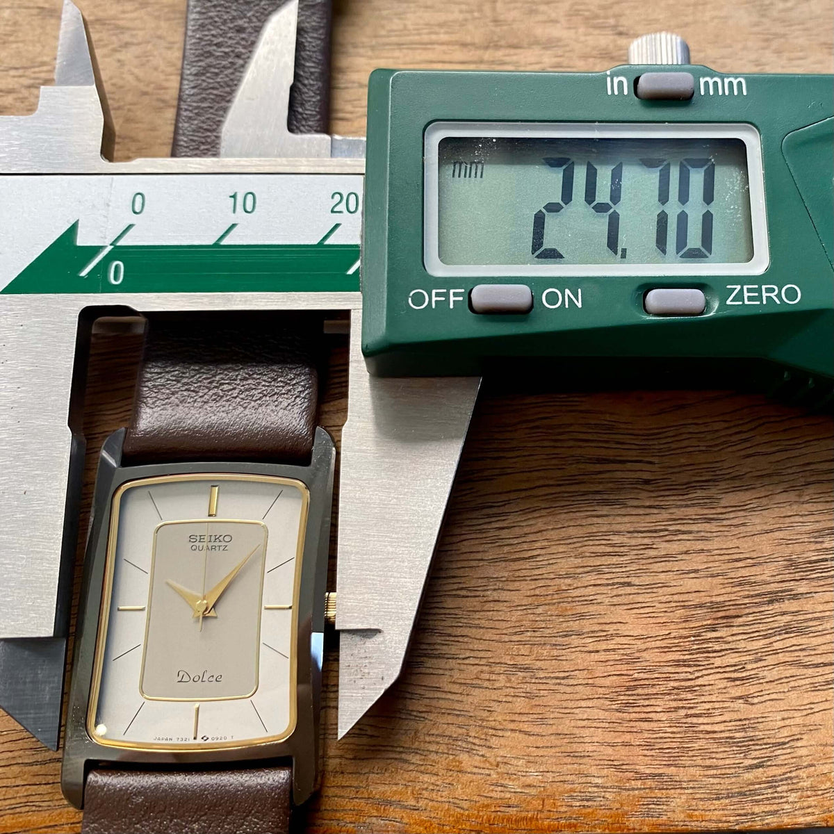 Vintage Seiko Dolce Quartz Tank 7321-5490 displayed with calipers measuring 24.00mm on a wooden background.