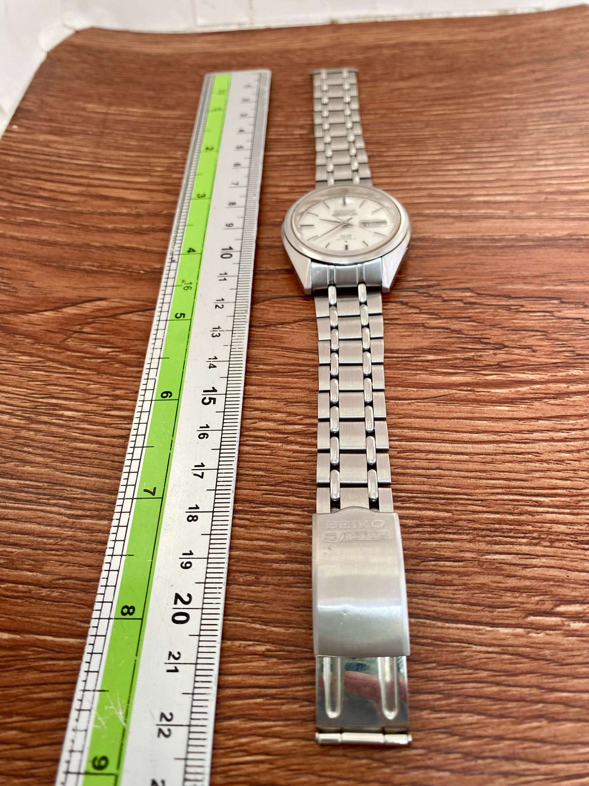 Vintage Seiko 5 SS Actus 6106-7510 on a wooden table next to a ruler for size reference