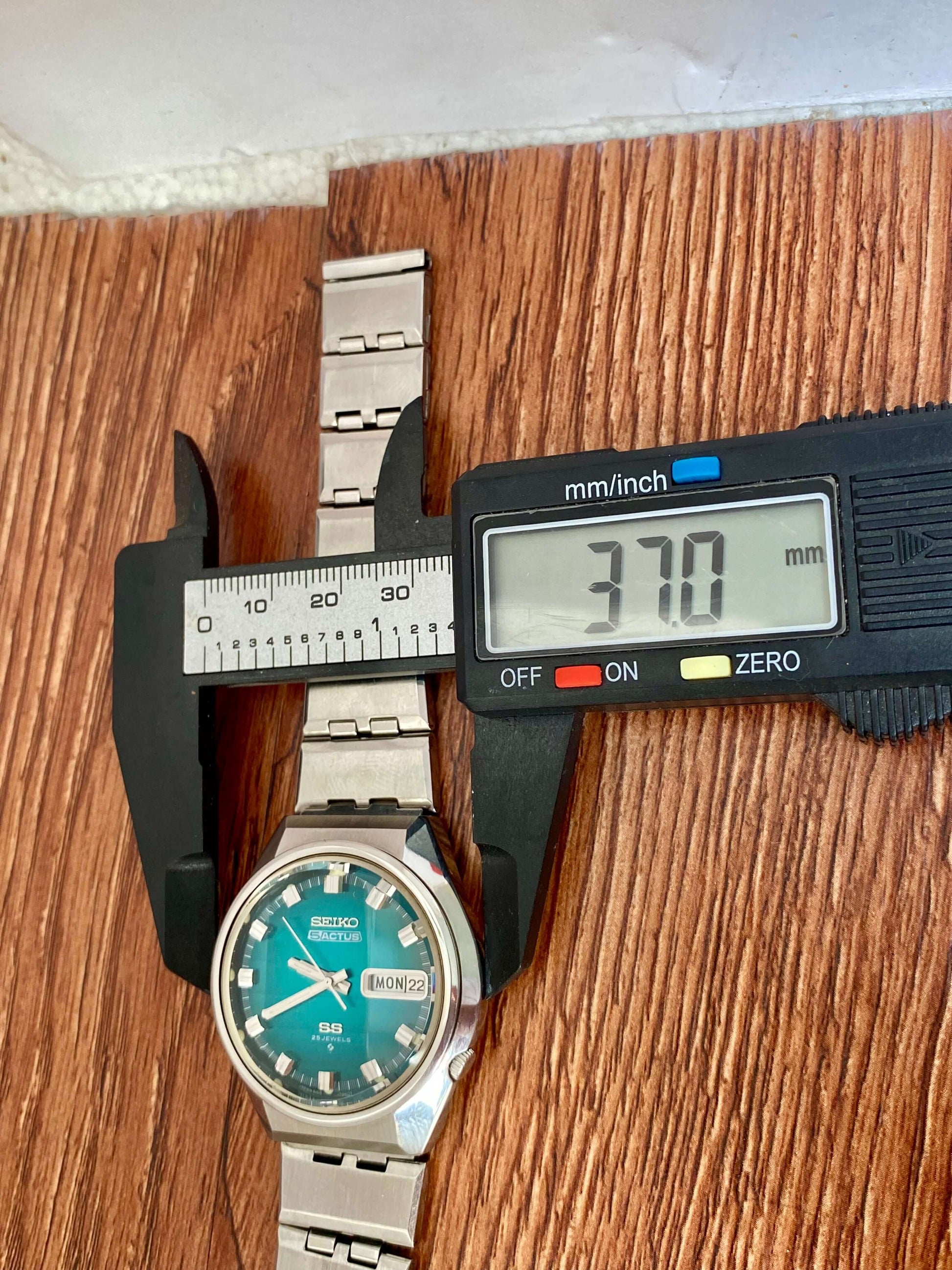 Vintage Seiko 5 Actus 6106-7690 with turquoise dial displaying a measurement of 37 mm using a caliper.