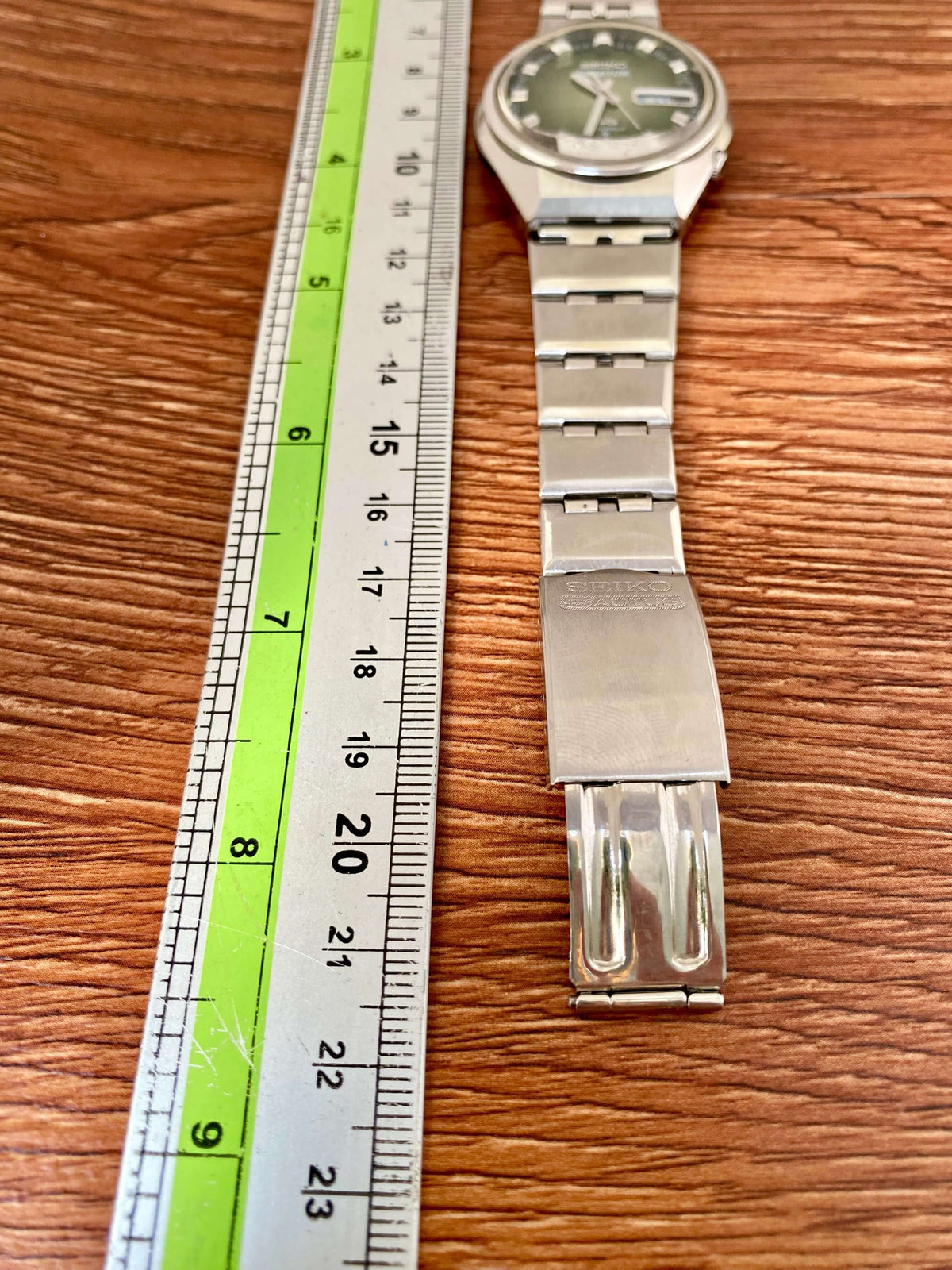 Vintage Seiko 5 Actus 6106-7690 with green dial and stainless steel bracelet next to a ruler for measurement