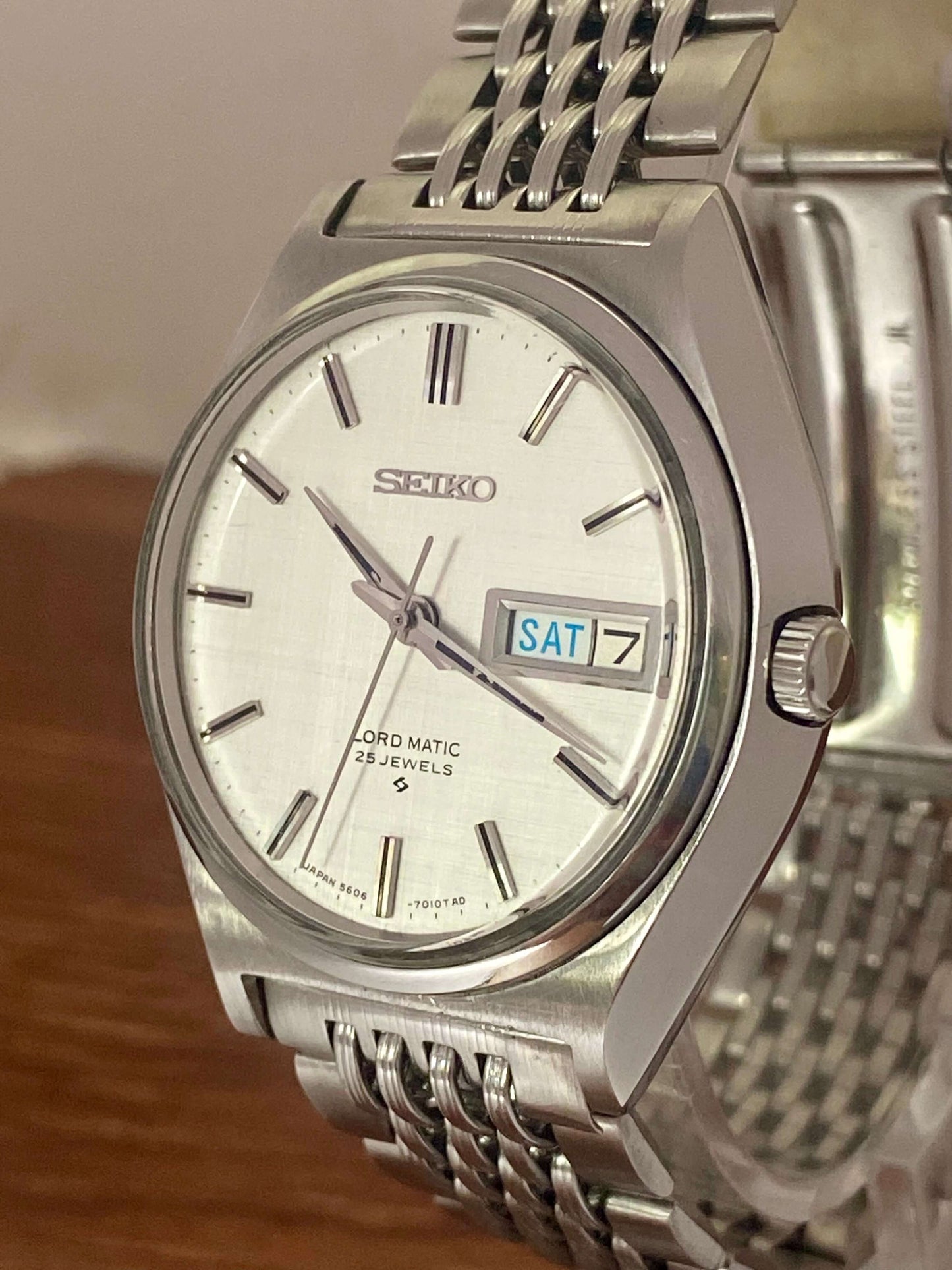 Vintage Seiko Lord Matic 5606-7010 watch with original white linen dial and stainless steel bracelet.