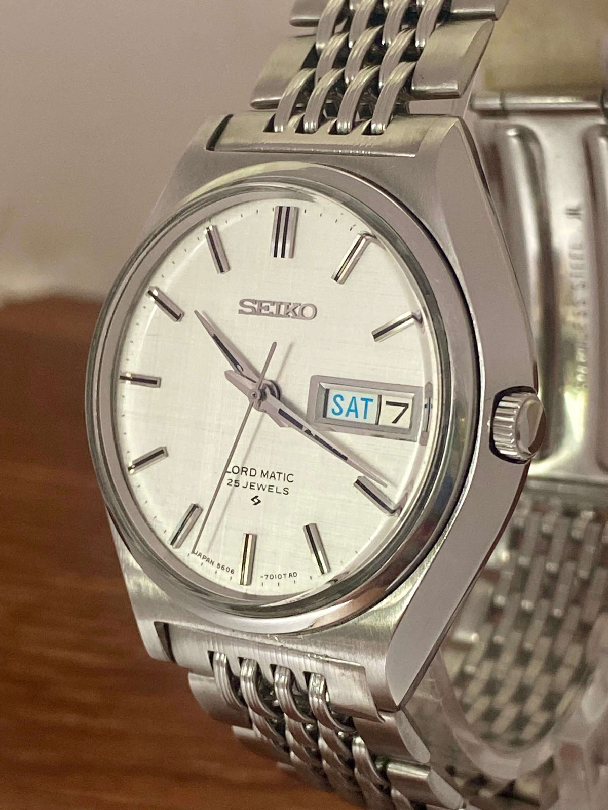 Vintage Seiko Lord Matic 5606-7010 watch with original white linen dial and stainless steel bracelet.