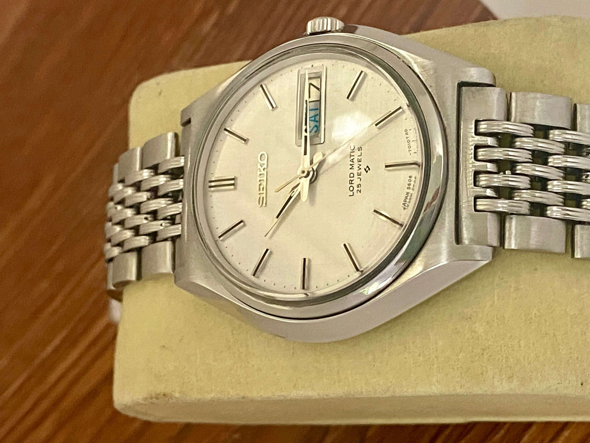 Vintage Seiko Lord Matic 5606-7010 on display with original white linen dial and metal bracelet.