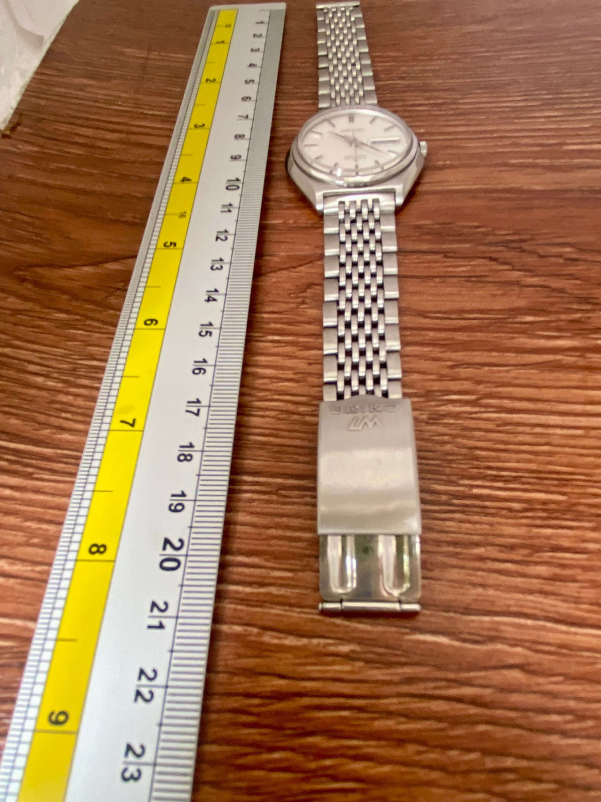 Vintage Seiko Lord Matic 5606-7010 with metallic bracelet alongside a ruler for size comparison