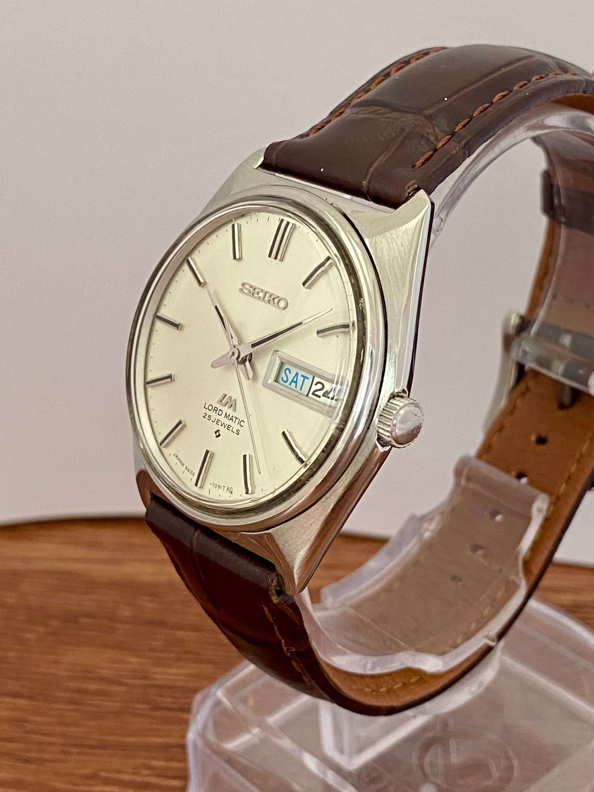 Vintage Seiko Lord Matic 5606-7000 automatic watch with brown leather strap and bilingual day/date display.