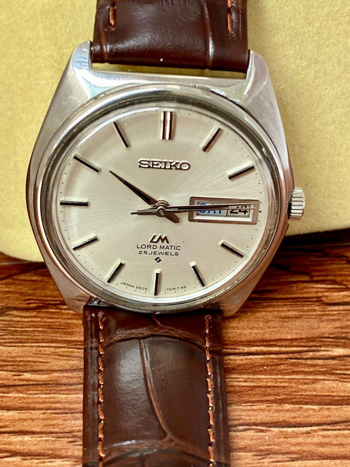 Vintage Seiko Lord Matic 5606-7000 watch with silver dial and brown leather strap.