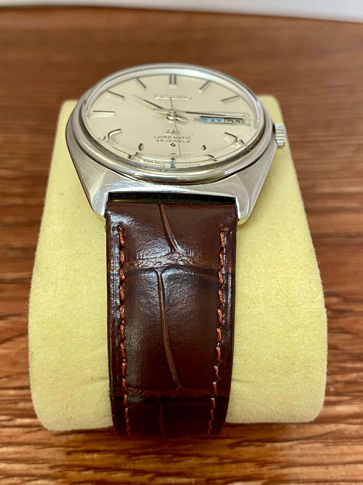 Vintage Seiko Lord Matic 5606-7000 watch with silver dial and brown leather strap on display.