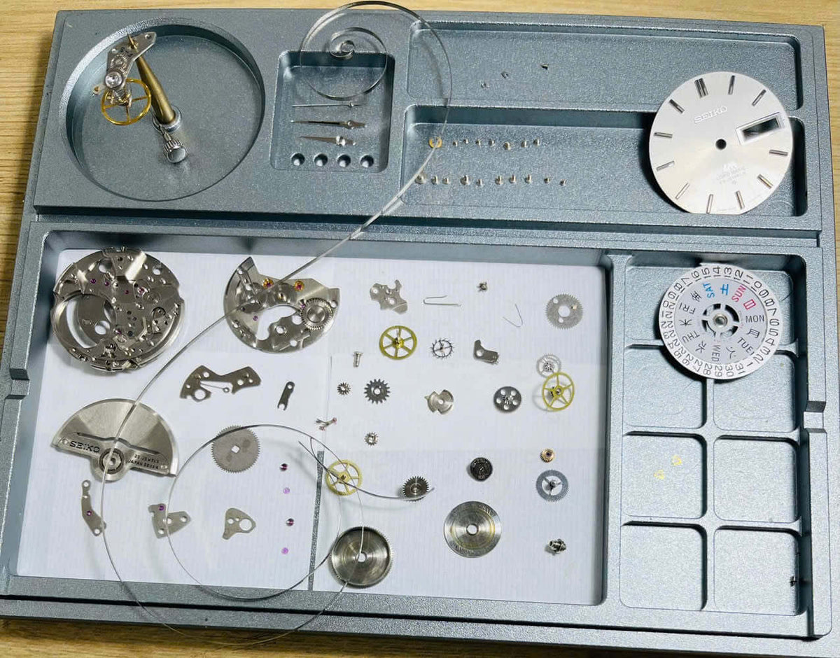 Vintage Seiko Lord Matic 5606-7000 watch movement parts displayed on a tray.